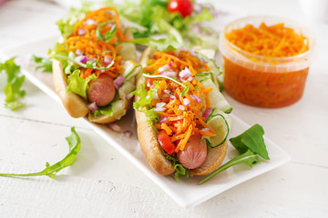 Hot dog with  cucumber, carrot, tomato and lettuce on wooden background. Fast food menu.