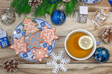 New Year's table with fir branches and decorations on a wooden background. Christmas tea with cookies, gingerbread, small stars. Festive background in blue tones.