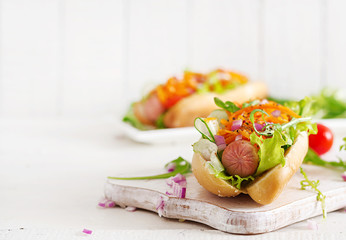 Hot dog with  cucumber, carrot, tomato and lettuce on wooden background. Fast food menu.