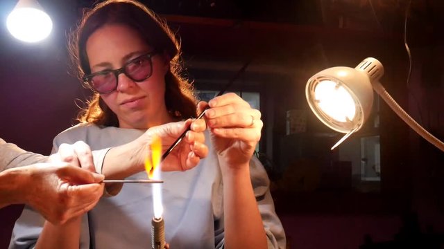 Student Learning to Apply Melted Glass to Mandrel While Beadmaking