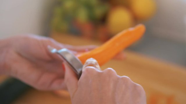 beautiful lady with red nails is peeling a carott
