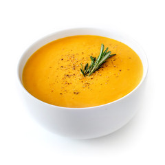 Bowl of pumpkin and carrot cream soup isolated on white background