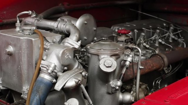 Panning shot of the engine of an old, red double-decker bus coach.