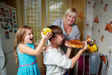 Family in the kitchen. Boy is trying to taste the cake. Mother, son and daughter playing together