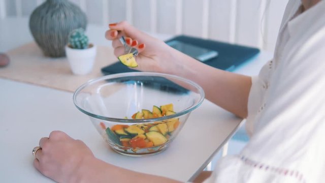 young and lovely dressed woman eating vegetable dinner while working