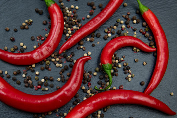 Red hot chili peppers with mixed peppercorns on dark background
