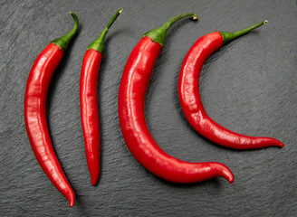 Red chili peppers in a row. Spicy ingredients on dark background