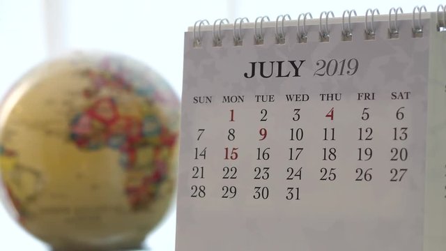 Motion of July 2019 calendar with blur earth globe turning background