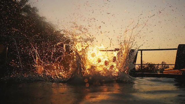 Silhouette of young man jumps in swimming pool water at Sunset through the sun durting beautiful sunset. slow motion. 1920x1080