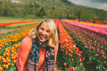 A senior woman smiling in a tulip field. 