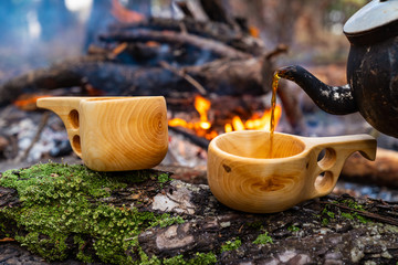 wooden finnish mug, called Kuksa on the stump, with camp fire