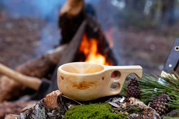 Foto auf Alu-Dibond wooden finnish mug, called Kuksa on the stump, with camp fire © shodography