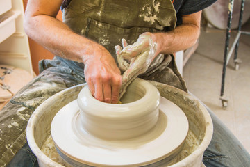     Artist potter in the workshop creating a jug out of earthenware, hands closeup. Twisted...