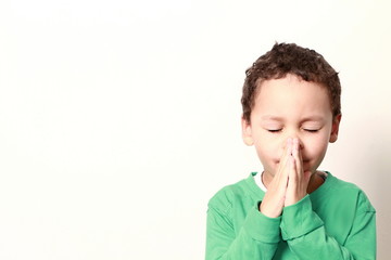 little boy praying with his hands clenched together