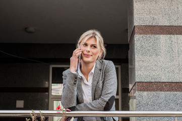 Fototapeta premium A girl in a business style with a mobile phone. A mysterious look. Smile