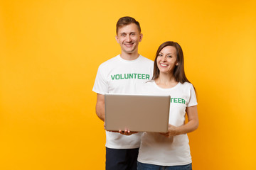 Colleagues couple in white t-shirt with inscription green volunteer using typing laptop pc computer...