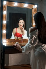 Woman in bra and bathrobe against mirror shot