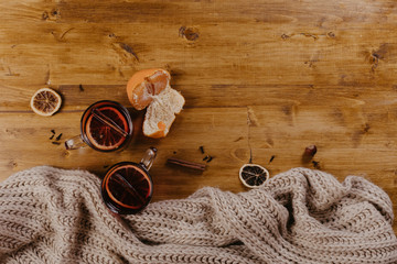 Mulled wine in mugs with scarf on wooden table.
