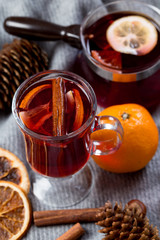 Mulled wine in glasses with orange and spices with gray scarf.