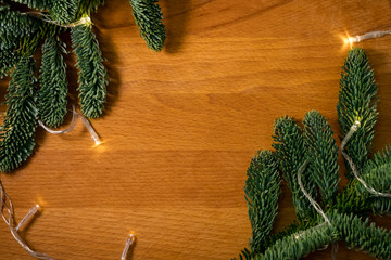Christmas composition. Christmas tree branches with garland on the wooden background