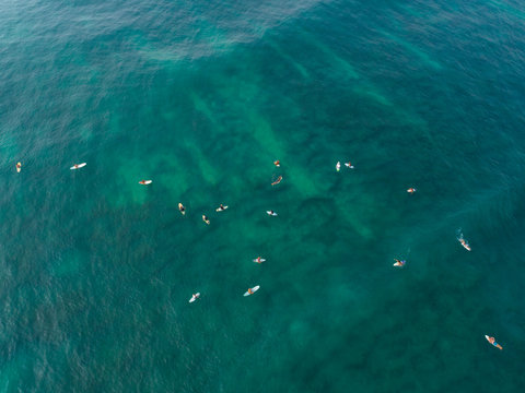 Aerial view from drone of surfers paddling for catching waves during surfing  in the indian ocean