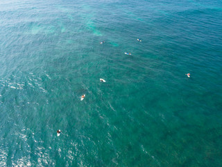 Fototapeta na wymiar Aerial view from drone of surfers paddling for catching waves during surfing in the indian ocean