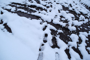 Beautiful background of snow and black dots of earth. Texture.