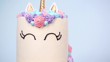 Gourmet unicorn cake with pink and purple buttercream frosting on blue background. - Powered by Adobe