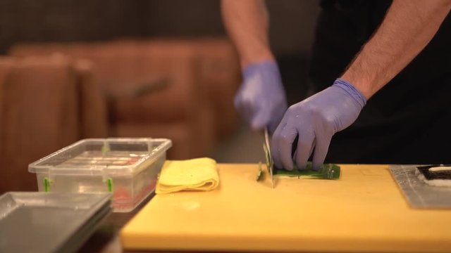 Chef slicing cucumber peel.Process of making sushi roll.