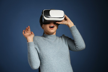 Young woman with virtual reality glasses on color background