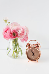 pink flowers and alarm clock in white background