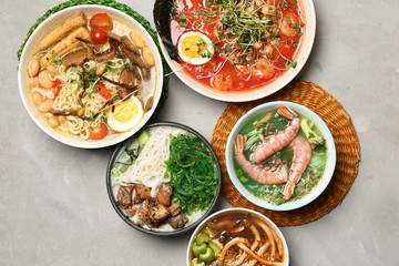 Assortment of tasty Chinese soups on grey table