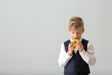 Cute little boy with donut on light background