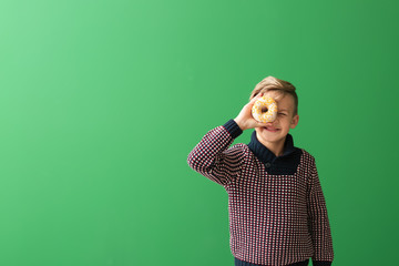 Cute little boy with donut on color background