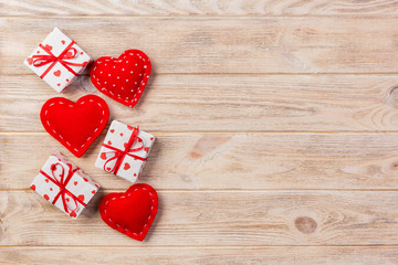 Fototapeta premium Valentine or other holiday handmade present in paper with red hearts and gifts box in holiday wrapper. Present box of gift on orange wooden table top view with copy space, empty space for design