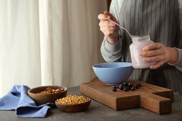 Woman preparing tasty granola in kitchen