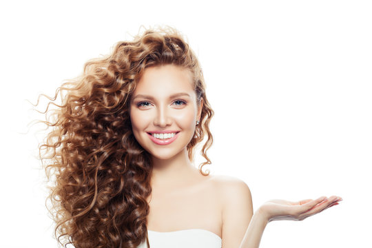 Cheerful woman with long curly hair, clear skin and empty open hand isolated on white background