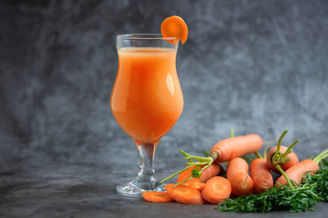 Glasses of carrot juice with vegetables on grey table. Side view