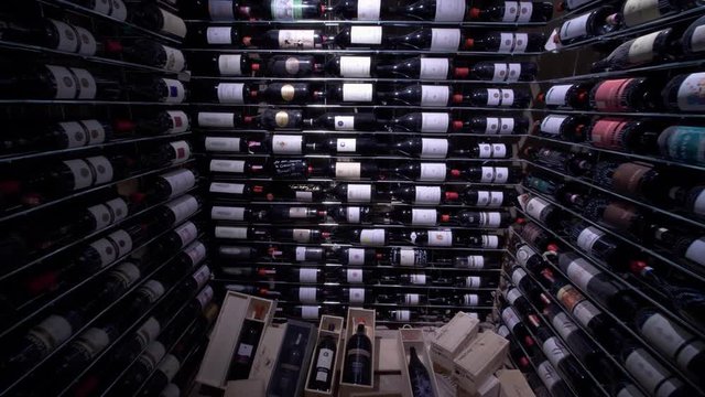 A wine cellar filled with shelves of many bottles of wine and boxes on the floor.