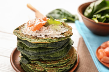 Tasty green pancakes with cottage cheese and salmon on table