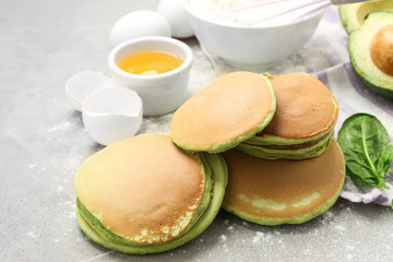 Tasty green pancakes with products on grey table
