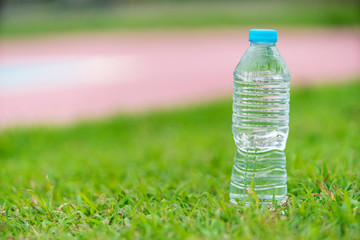 A bottle of water on green grass with copy space.