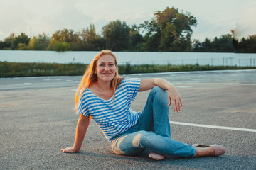 Fototapeta na wymiar Young woman siting on asfalt looking at camera