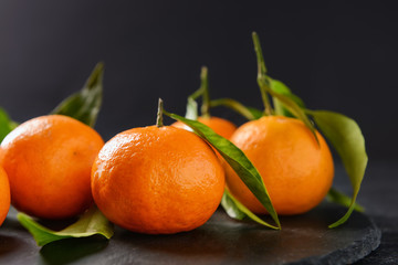Slate plate with tasty tangerines on table, closeup