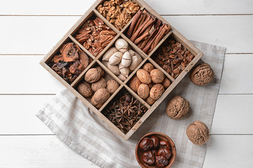 Assortment of nuts and spices in divided box on white wooden table