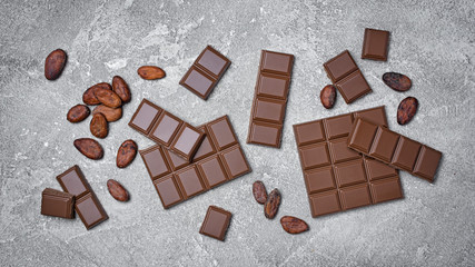 Top view of broken chocolate bars with cocoa beans as ingredient for confectionery