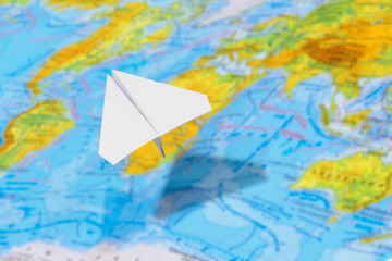 Fototapeta na wymiar small paper airplane over a geographical map of the world. selective focus. Concept: air travel, cargo delivery, travel, international messages, mail.