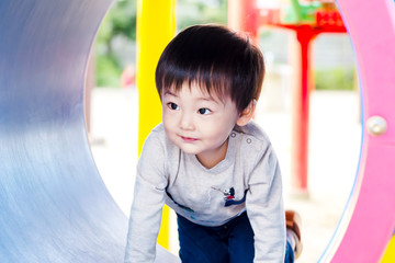 公園の遊具のトンネルを這って遊ぶ男の子