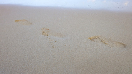 Footprint on sand beach with water waves background 