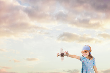 Girl in an old style knitted pilot helmet holding toy airplane